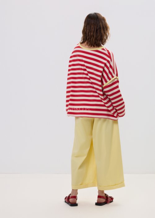 Bluza damska oversize w czerwono-kremowe paski z długim rękawem i kontrastowym, żółtym wykończeniem przy dekolcie oraz rękawach. Luźny, wygodny fason w stylu casual, idealny do codziennych stylizacji.