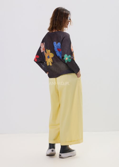 Żółte spodnie damskie z szeroką nogawką i elastycznym pasem, o luźnym, wygodnym kroju. Lekkie spodnie w pastelowym odcieniu żółci zestawione z trampkami w swobodnej, miejskiej stylizacji.