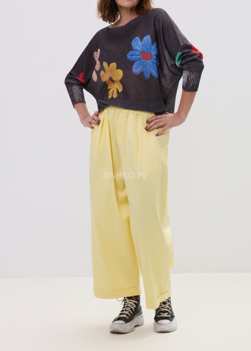 Żółte spodnie damskie z szeroką nogawką i elastycznym pasem, o luźnym, wygodnym kroju. Lekkie spodnie w pastelowym odcieniu żółci zestawione z trampkami w swobodnej, miejskiej stylizacji.