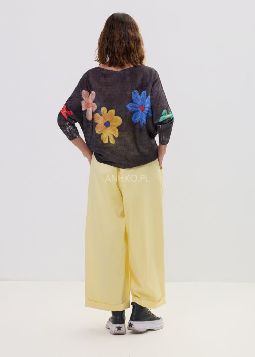 Żółte spodnie damskie z szeroką nogawką i elastycznym pasem, o luźnym, wygodnym kroju. Lekkie spodnie w pastelowym odcieniu żółci zestawione z trampkami w swobodnej, miejskiej stylizacji.