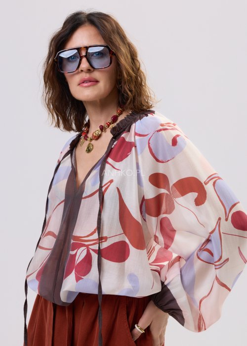 Damski naszyjnik z czerwonych koralików z ozdobnymi złotymi zawieszkami i medalionem.