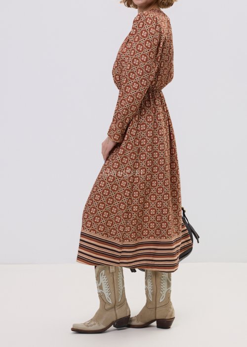 Wzorzysta sukienka midi z wiskozy w retro print w odcieniach brązu, z marszczonym dekoltem i gumką w pasie. Stylizacja z jasnymi kowbojkami i czarną torebką podkreśla modowy charakter modelu.