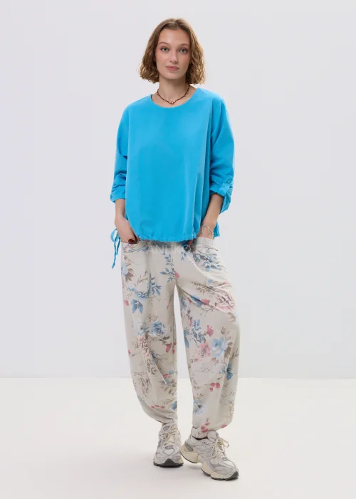 Niebieska bluzka damska o luźnym kroju z długim rękawem, regulowane wiązania i elastyczne wykończenie, casualowy styl.