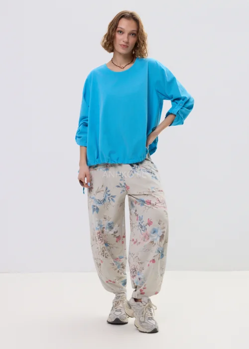 Niebieska bluzka damska o luźnym kroju z długim rękawem, regulowane wiązania i elastyczne wykończenie, casualowy styl.