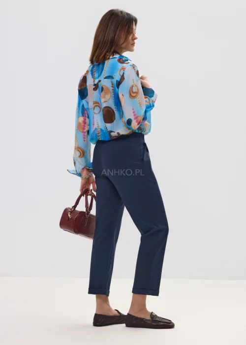 Koszula damska w artystyczny print w odcieniach niebieskiego i brązu, lekka tkanina, klasyczny kołnierz – elegancka stylizacja z granatowymi spodniami.