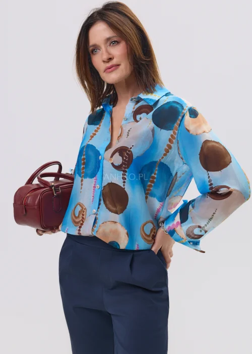 Koszula damska w artystyczny print w odcieniach niebieskiego i brązu, lekka tkanina, klasyczny kołnierz – elegancka stylizacja z granatowymi spodniami.