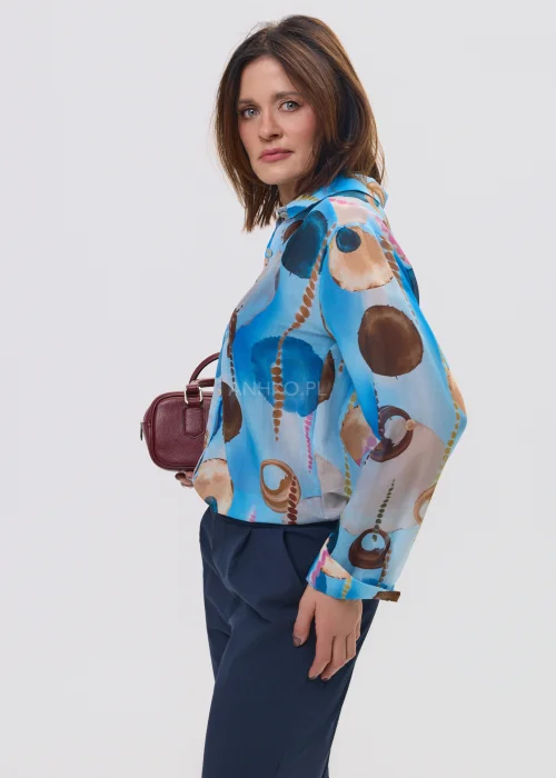 Koszula damska w artystyczny print w odcieniach niebieskiego i brązu, lekka tkanina, klasyczny kołnierz – elegancka stylizacja z granatowymi spodniami.