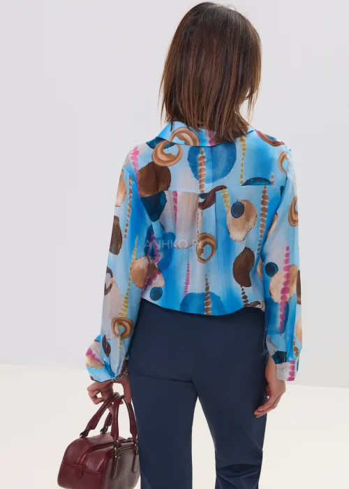 Koszula damska w artystyczny print w odcieniach niebieskiego i brązu, lekka tkanina, klasyczny kołnierz – elegancka stylizacja z granatowymi spodniami.