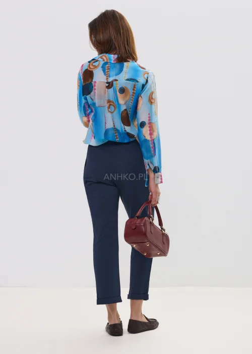 Koszula damska w artystyczny print w odcieniach niebieskiego i brązu, lekka tkanina, klasyczny kołnierz – elegancka stylizacja z granatowymi spodniami.