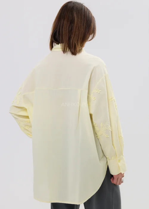 Koszula damska oversize w pastelowym żółtym kolorze, lekka transparentna tkanina z haftowanymi detalami – elegancka stylizacja ze spodniami.