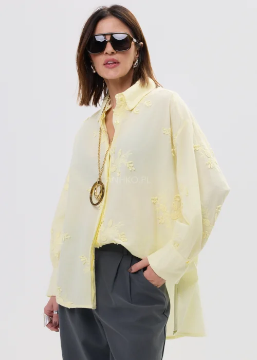 Koszula damska oversize w pastelowym żółtym kolorze, lekka transparentna tkanina z haftowanymi detalami – elegancka stylizacja ze spodniami.