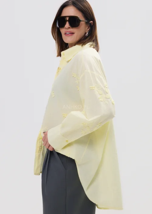 Koszula damska oversize w pastelowym żółtym kolorze, lekka transparentna tkanina z haftowanymi detalami – elegancka stylizacja ze spodniami.