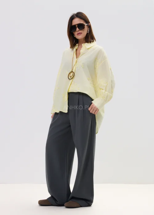 Koszula damska oversize w pastelowym żółtym kolorze, lekka transparentna tkanina z haftowanymi detalami – elegancka stylizacja ze spodniami.