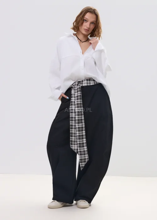 Biała koszula damska oversize z długim rękawem i klasycznym kołnierzykiem, luźny fason, minimalistyczna stylizacja.