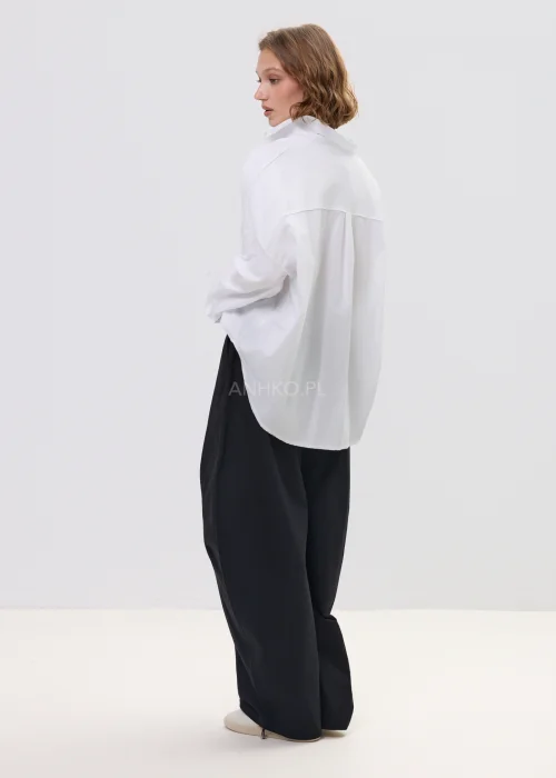 Biała koszula damska oversize z długim rękawem i klasycznym kołnierzykiem, luźny fason, minimalistyczna stylizacja.