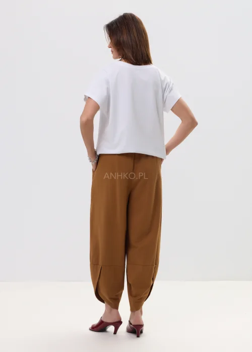 Biały t-shirt z nadrukiem czerwonych papryczek na tle panterki i napisem „PICANTE”, luźny fason – stylizacja z brązowymi spodniami.