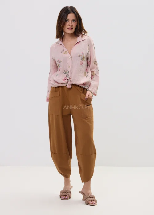 Różowa koszula damska w kwiatowy wzór, wiązana na dole, z kołnierzykiem i guzikami, lekka stylizacja casual.