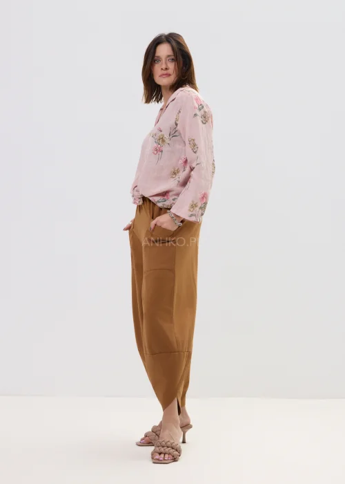 Różowa koszula damska w kwiatowy wzór, wiązana na dole, z kołnierzykiem i guzikami, lekka stylizacja casual.