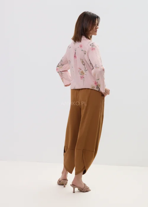 Różowa koszula damska w kwiatowy wzór, wiązana na dole, z kołnierzykiem i guzikami, lekka stylizacja casual.