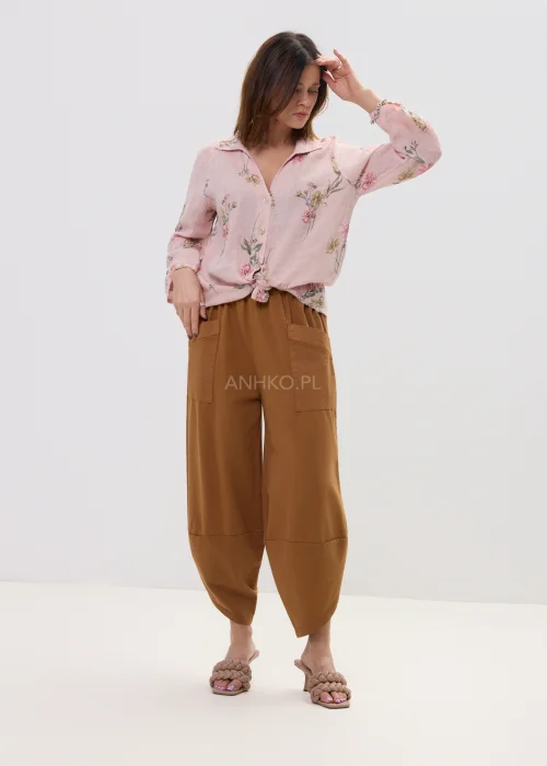 Różowa koszula damska w kwiatowy wzór, wiązana na dole, z kołnierzykiem i guzikami, lekka stylizacja casual.