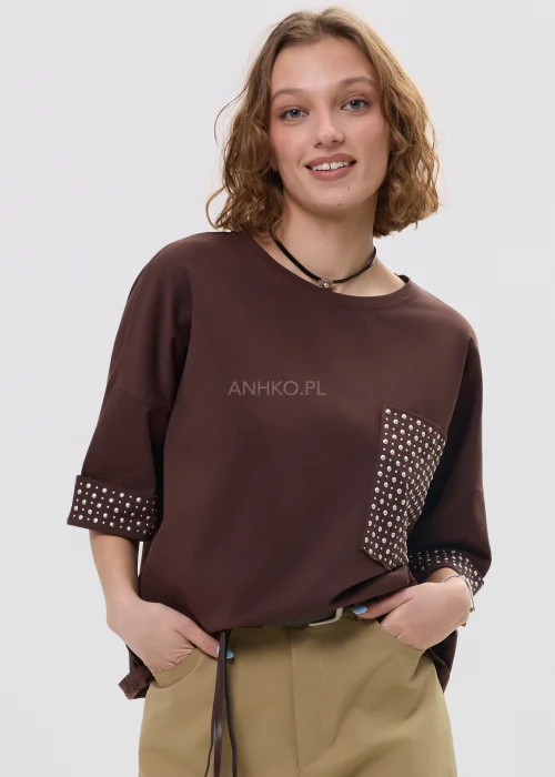 Brązowa bluzka oversize z krótkim rękawem, kieszonka i mankiety zdobione ćwiekami, casualowa stylizacja.