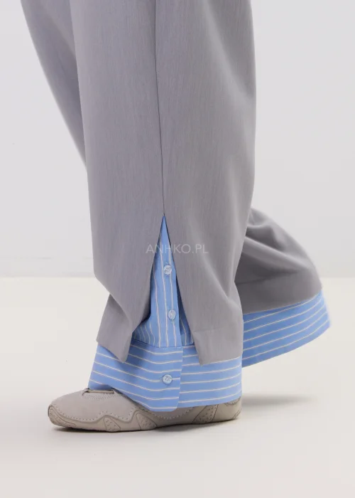 Szerokie spodnie damskie typu wide leg w kolorze szarym z wysokim stanem, elegancki fason – stylizacja ze sneakersami i koszulą.