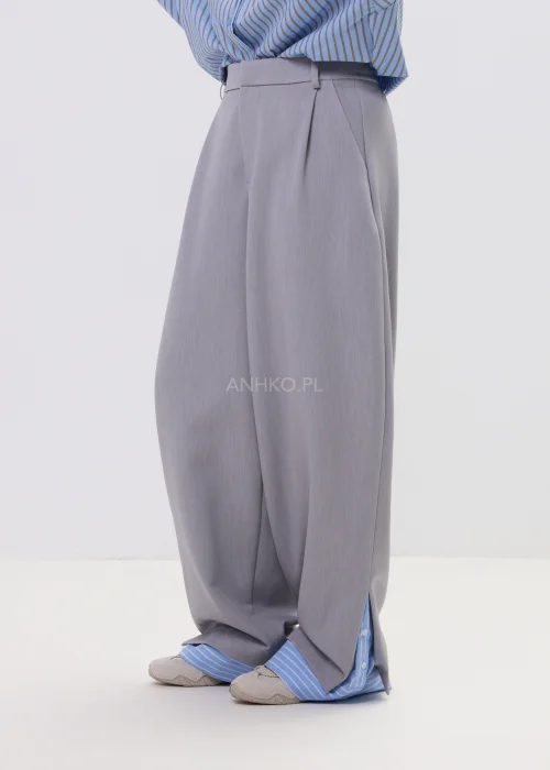 Szerokie spodnie damskie typu wide leg w kolorze szarym z wysokim stanem, elegancki fason – stylizacja ze sneakersami i koszulą.