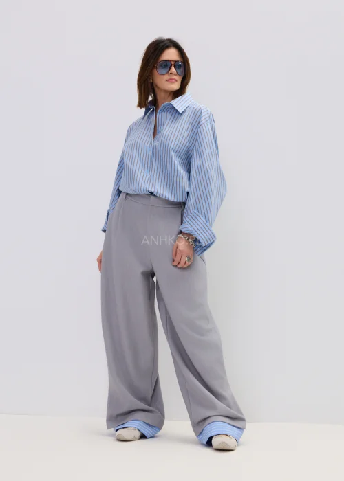 Koszula oversize w niebieskie paski z kołnierzykiem i zapięciem na guziki, luźny fason – stylizacja z eleganckimi spodniami i okularami przeciwsłonecznymi.