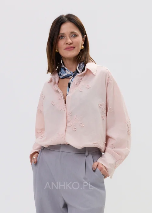 Koszula oversize pudrowy róż z delikatnym haftem kwiatowym, lekka i zwiewna, zapinana na guziki – elegancka stylizacja z apaszką i spodniami w kant.