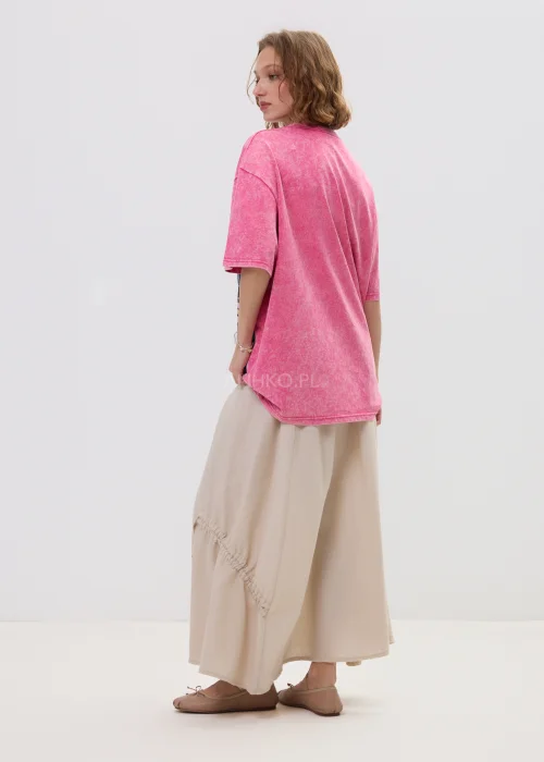 Różowy t-shirt damski oversize z nadrukiem postaci i cekinowymi detalami, luźny fason – stylizacja ze spódnicą.