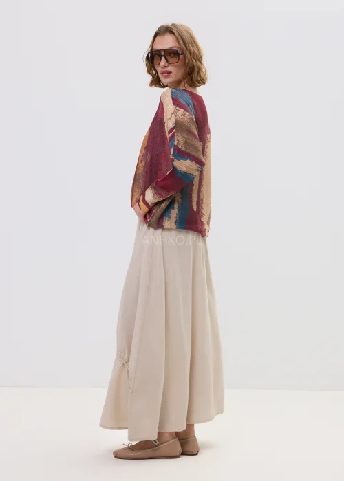 Sweter oversize w wielokolorowy, artystyczny print – odcienie bordo, beżu i niebieskiego, luźny fason, stylizacja z jasną spódnicą.