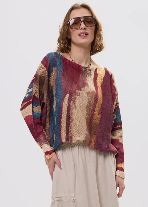 Sweter oversize w wielokolorowy, artystyczny print – odcienie bordo, beżu i niebieskiego, luźny fason, stylizacja z jasną spódnicą.