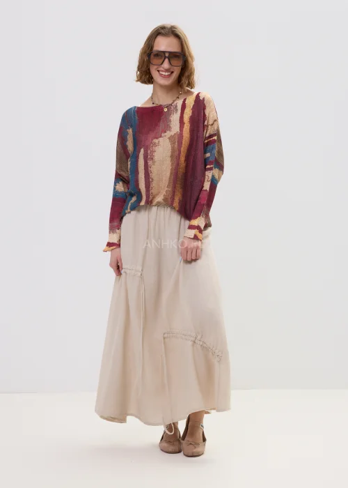 Sweter oversize w wielokolorowy, artystyczny print – odcienie bordo, beżu i niebieskiego, luźny fason, stylizacja z jasną spódnicą.