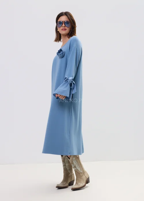 Sukienka damska midi w kolorze błękitnym, o luźnym, rozkloszowanym kroju z długim rękawem i wiązaniem przy mankietach, ozdobiona subtelną aplikacją – wygodna i stylowa propozycja na co dzień.