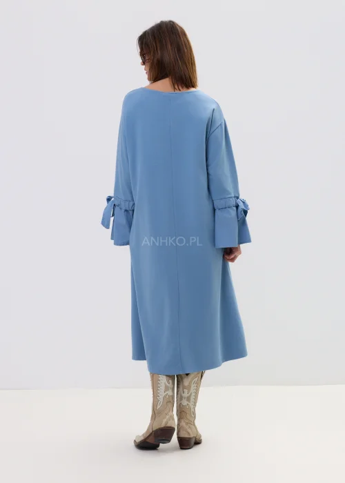 Sukienka damska midi w kolorze błękitnym, o luźnym, rozkloszowanym kroju z długim rękawem i wiązaniem przy mankietach, ozdobiona subtelną aplikacją – wygodna i stylowa propozycja na co dzień.