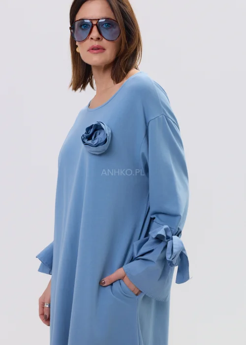 Sukienka damska midi w kolorze błękitnym, o luźnym, rozkloszowanym kroju z długim rękawem i wiązaniem przy mankietach, ozdobiona subtelną aplikacją – wygodna i stylowa propozycja na co dzień.