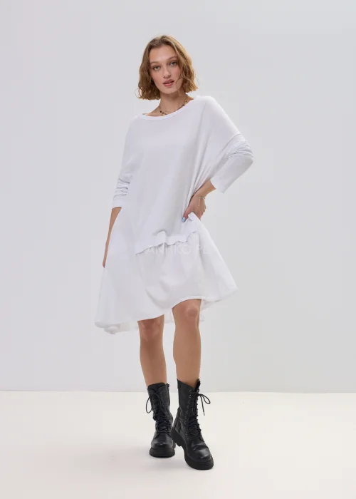 Biała sukienka oversize z falbaną u dołu, asymetryczny krój z dłuższym tyłem, stylizacja z botkami.