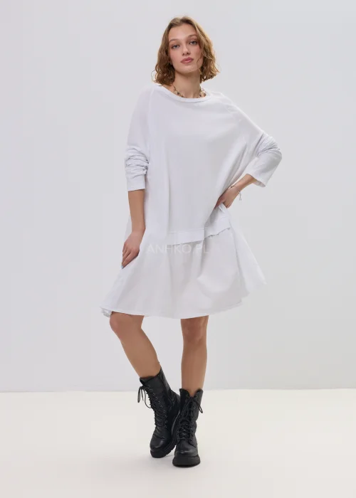 Biała sukienka oversize z falbaną u dołu, asymetryczny krój z dłuższym tyłem, stylizacja z botkami.