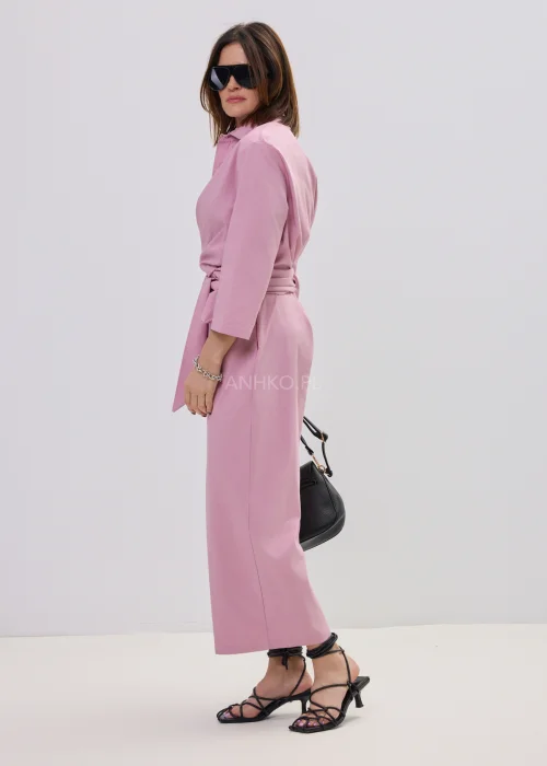 Różowy kombinezon damski z kopertowym dekoltem i wiązaniem w talii, elegancki fason z szerokimi nogawkami, stylizacja z sandałami na obcasie.