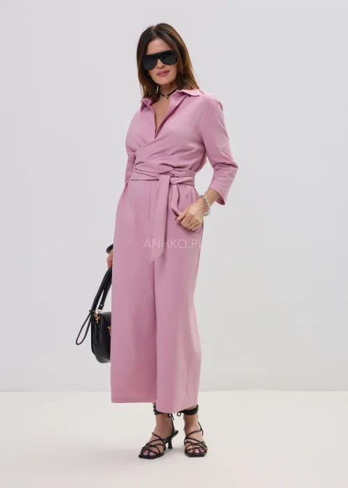 Różowy kombinezon damski z kopertowym dekoltem i wiązaniem w talii, elegancki fason z szerokimi nogawkami, stylizacja z sandałami na obcasie.