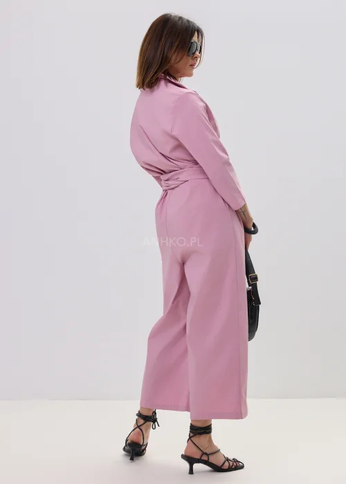 Różowy kombinezon damski z kopertowym dekoltem i wiązaniem w talii, elegancki fason z szerokimi nogawkami, stylizacja z sandałami na obcasie.