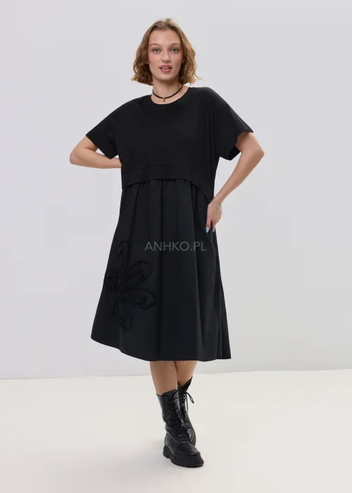 Czarna sukienka midi o luźnym fasonie z krótkim rękawem i ozdobnym detalem kwiatowym, minimalistyczny styl – stylizacja z botkami.