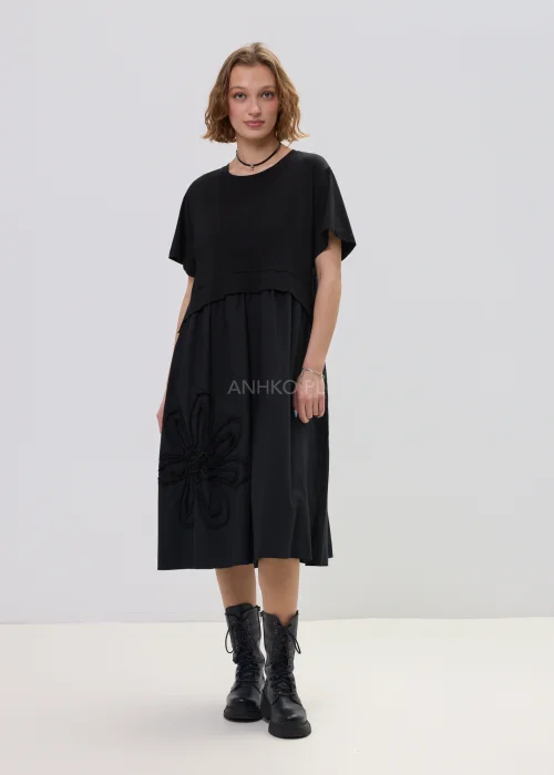 Czarna sukienka midi o luźnym fasonie z krótkim rękawem i ozdobnym detalem kwiatowym, minimalistyczny styl – stylizacja z botkami.