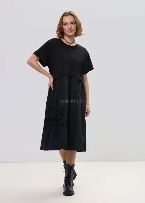 Czarna sukienka midi o luźnym fasonie z krótkim rękawem i ozdobnym detalem kwiatowym, minimalistyczny styl – stylizacja z botkami.