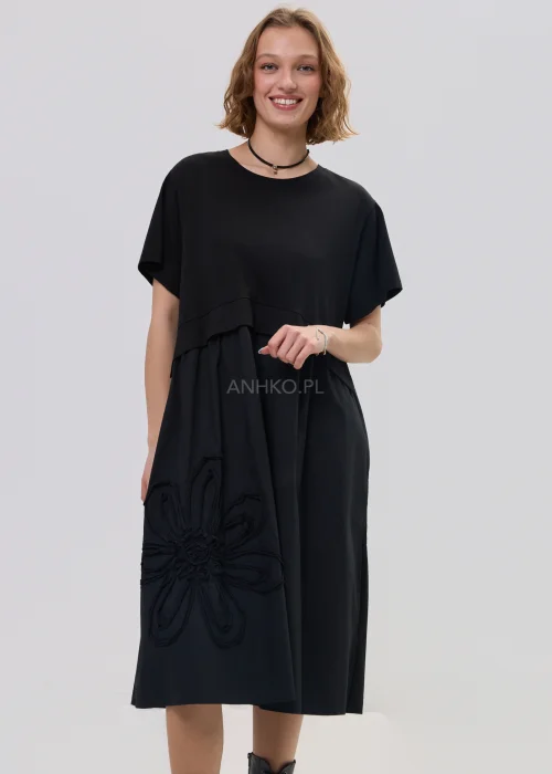 Czarna sukienka midi o luźnym fasonie z krótkim rękawem i ozdobnym detalem kwiatowym, minimalistyczny styl – stylizacja z botkami.