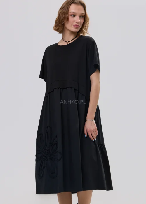 Czarna sukienka midi o luźnym fasonie z krótkim rękawem i ozdobnym detalem kwiatowym, minimalistyczny styl – stylizacja z botkami.