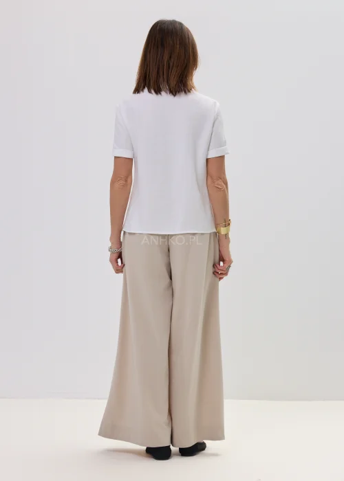 Beżowe spodnie damskie wide leg z wysokim stanem i szerokimi nogawkami, elegancki, lejący fason w nowoczesnej stylizacji.