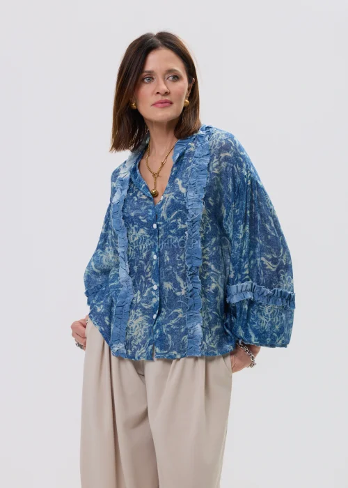Niebieska koszula damska oversize z printem i falbankami, zapinana na guziki, lekki materiał w stylowej, casualowej stylizacji.