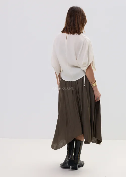 Spódnica midi brązowa o zwiewnym, asymetrycznym kroju z delikatnym połyskiem, stylizowana z szerokim paskiem z ozdobną klamrą i botkami na obcasie.