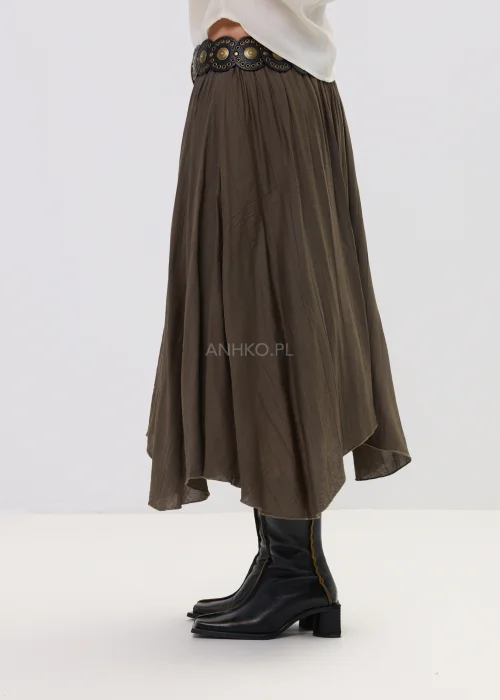Spódnica midi brązowa o zwiewnym, asymetrycznym kroju z delikatnym połyskiem, stylizowana z szerokim paskiem z ozdobną klamrą i botkami na obcasie.